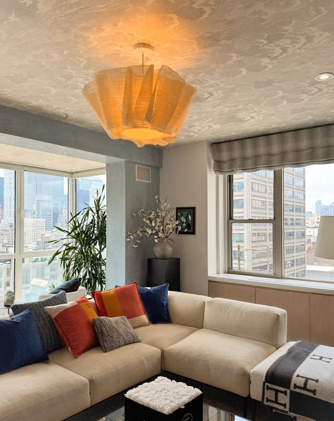 Cozy modern living room with beige sectional sofa and city view windows.