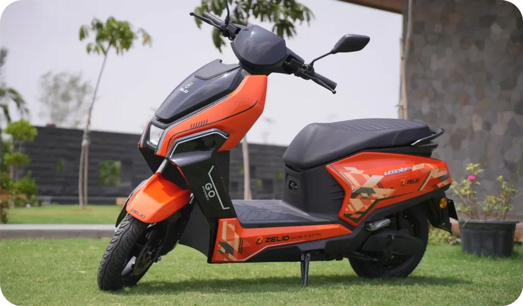 Orange and black electric scooter parked on grass.