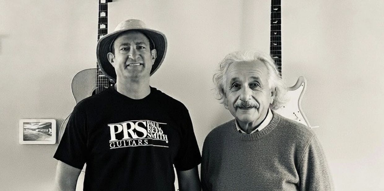 Two men stand side by side with guitars hanging on the wall behind them.