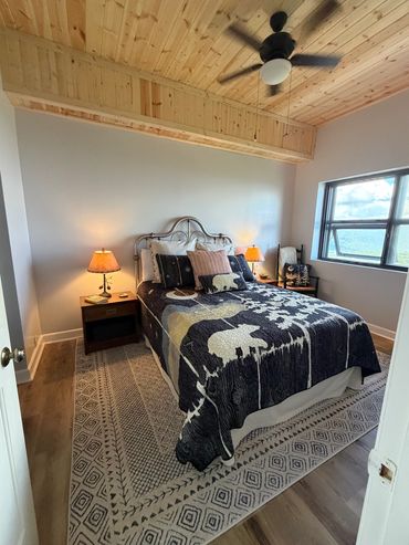 Cozy bedroom with nature-themed bedding and wooden ceiling.