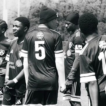 Young soccer players standing together outdoors in black and white photo.