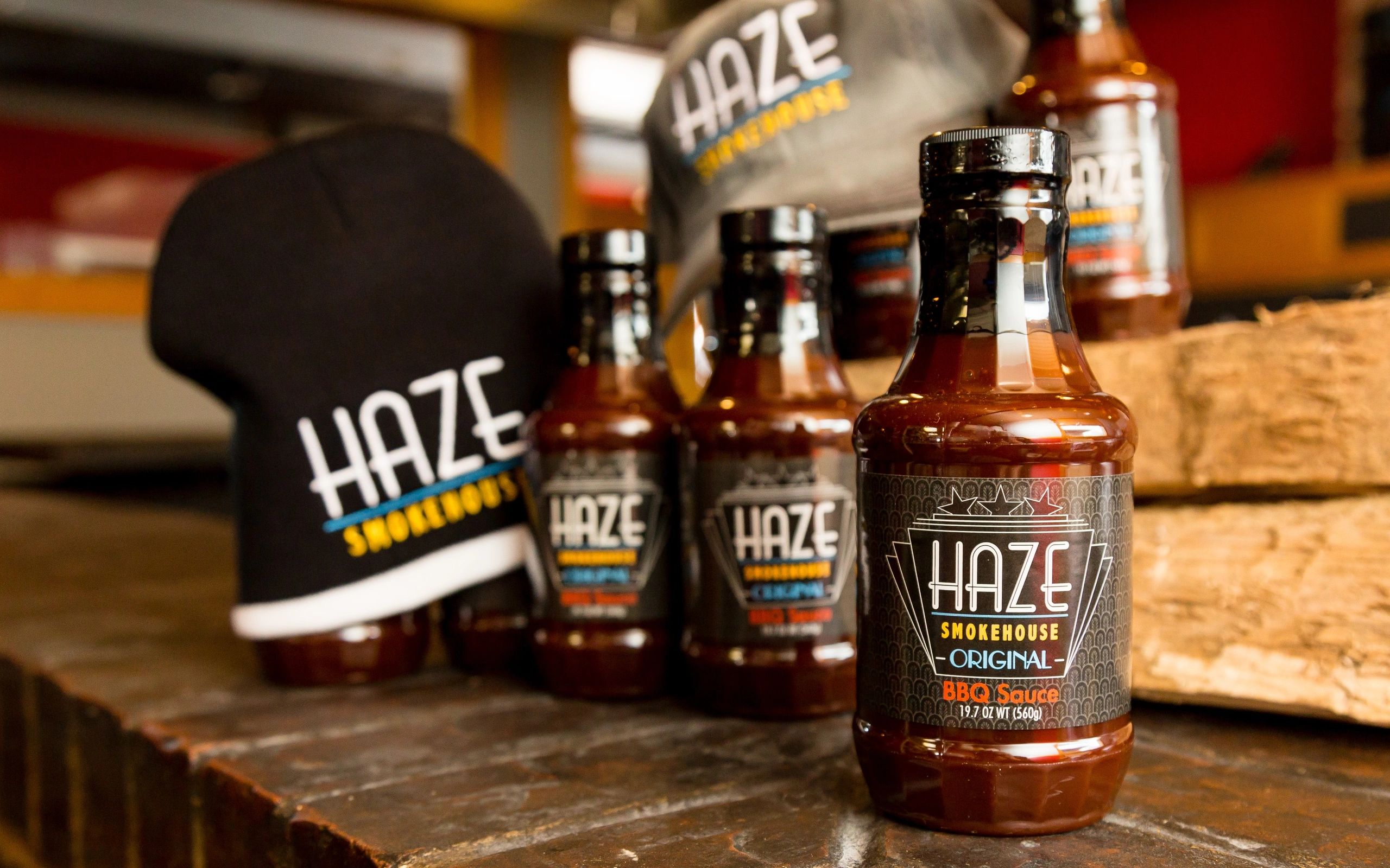 Bottles of barbeque sauce in front of hats with the restaurant logo