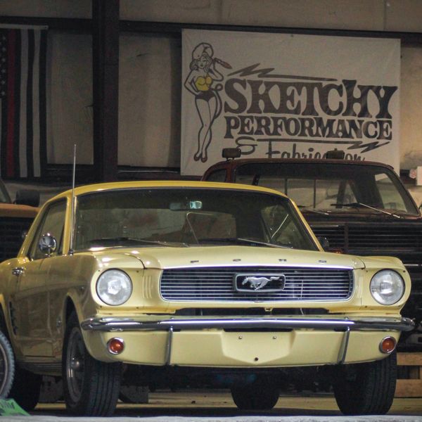 Yellow classic Ford Mustang in a garage.