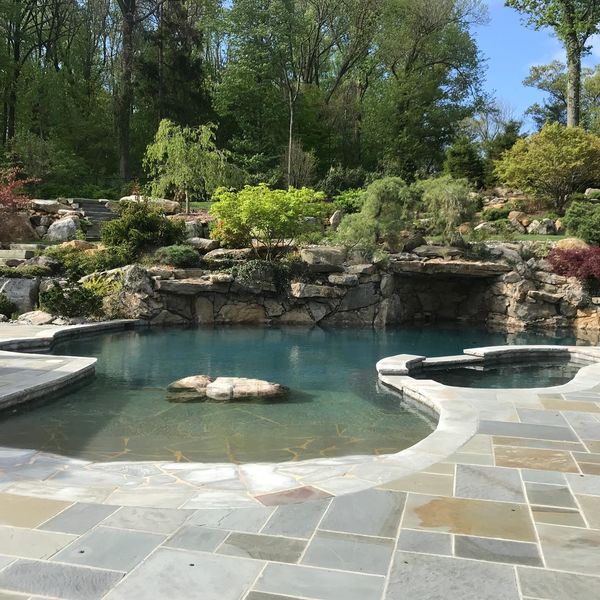 A serene outdoor pool surrounded by natural stone and greenery.