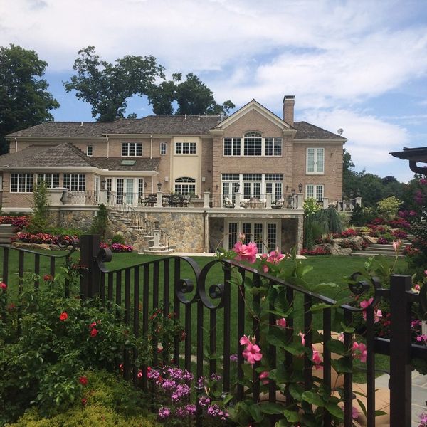 Large house with a garden and flowers behind a black fence.