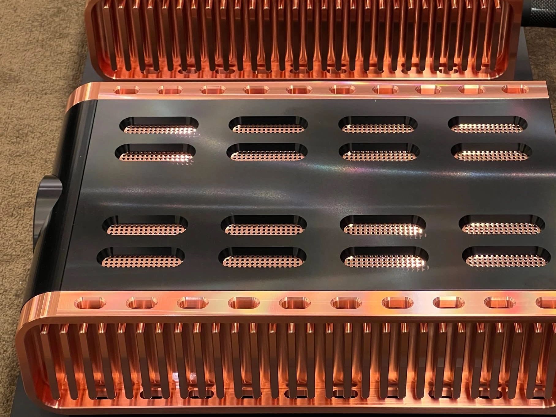 Close-up of black and copper metal components with ventilation slots.