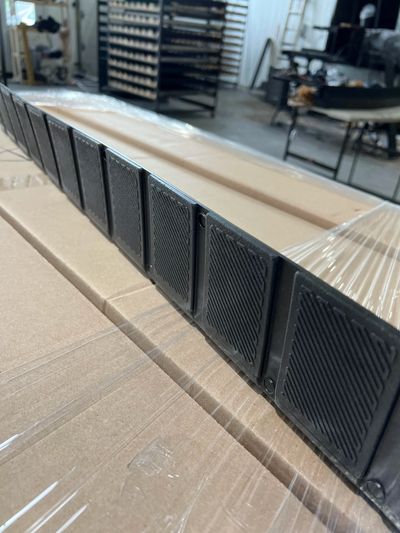 Close-up of black plastic grid panels on cardboard boxes in a warehouse.