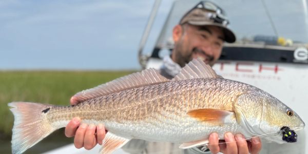 Man holding a large fish on a boat.