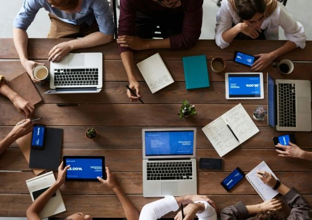 Team coordinating documents on devices, representing an organized outsourced notary department