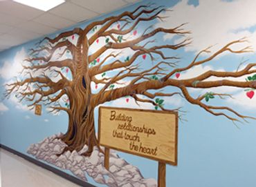 Large hospital mural of decorative tree, rocks, wood sign, leaves by Jill Roberts. Wildomar CA