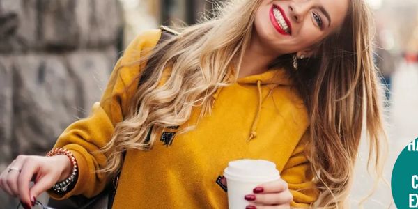 blonde woman in gold blouse with cup of coffee. smiling