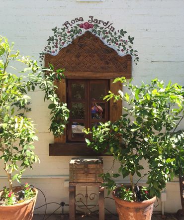 Rosa Jardin painted on white block wall around wood window frame in rose garden Palm Springs, CA