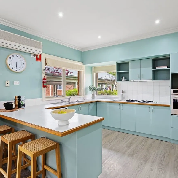 Bright kitchen with pastel blue cabinets and wooden stools at the counter.