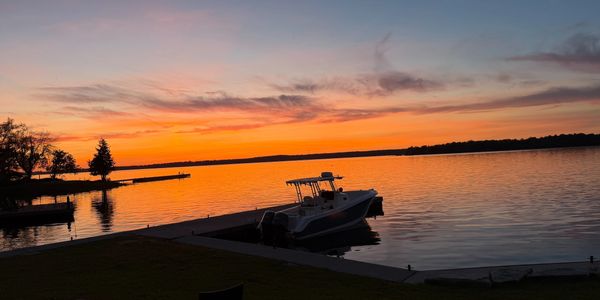 Boat docked at a pier during a vibrant sunset over calm water.