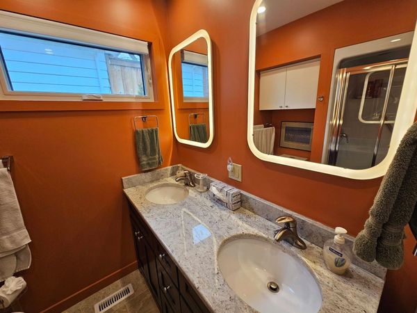 Modern bathroom with orange walls and double sink vanity.
