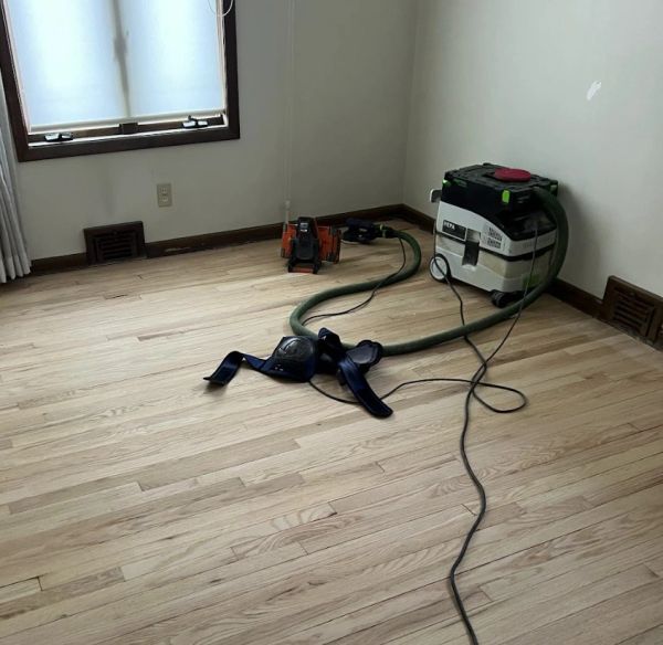 Hardwood floor sander connected to a dust-containment system in a Shaker Heights, Ohio bedroom.