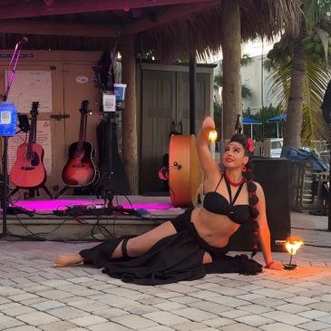 Polynesian dancer in front of stage with fire palms.