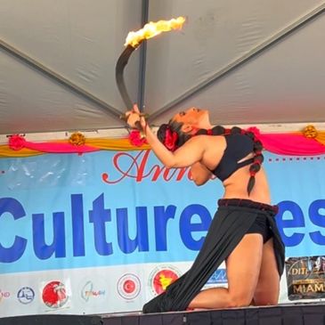 Bellydancer on stage with fire sword with banner in the background text: Asian Culture Festival 