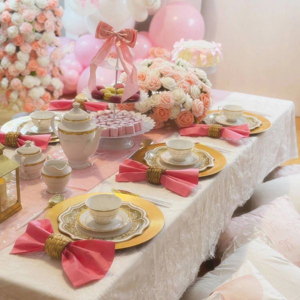 Elegant tea party setup with pink and gold accents and floral decorations.