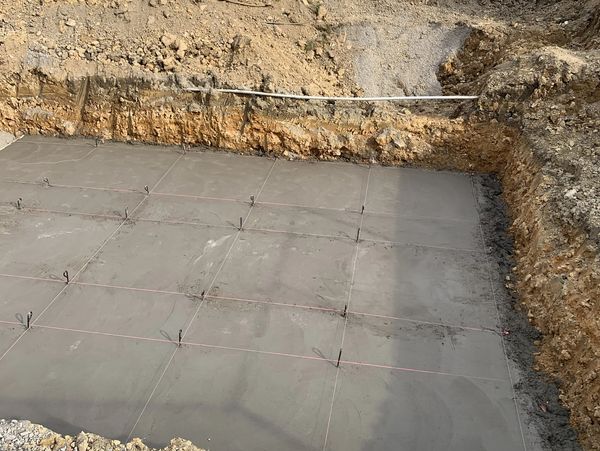 Concrete foundation laid at the center of a spot dug by excavators.