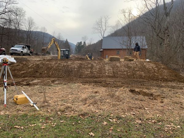Excavation site with residential site work being done with a excavator and skid steer in the backgro