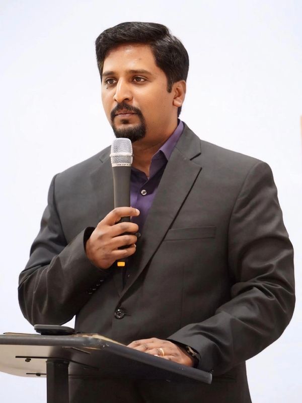 Man in suit speaking into a microphone at a podium.