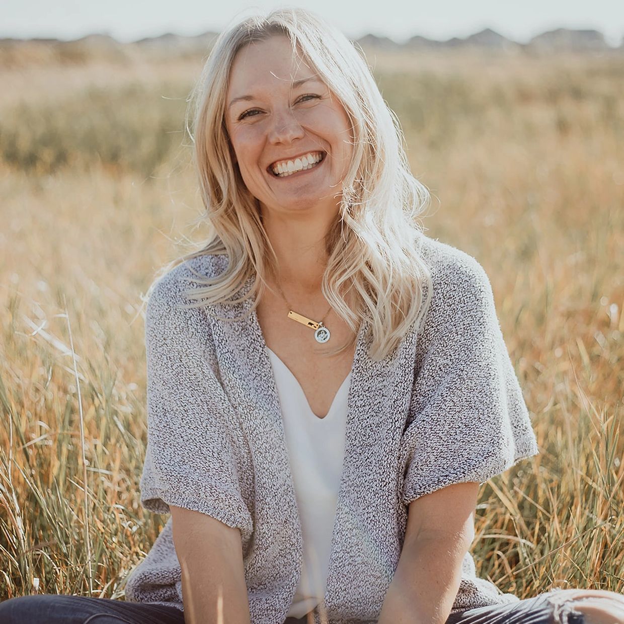 Smiling woman sitting outdoors in a field.