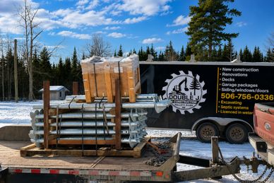 Construction materials loaded on a trailer next to a Double J construction trailer.