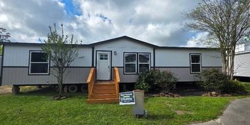 Double wide home with arched roof and wooden stairway
