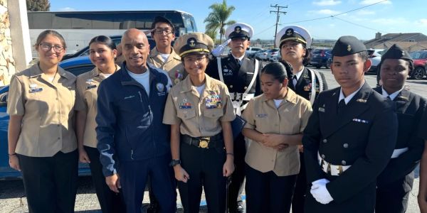 Group of young naval cadets and an adult in uniform outdoors.