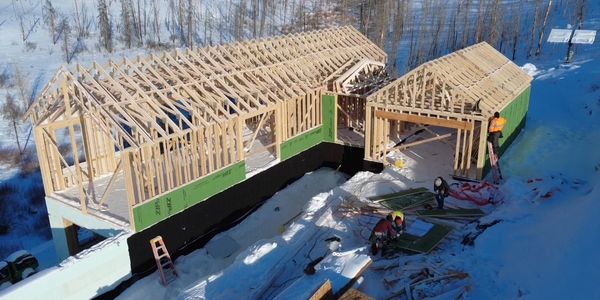 Framing stage of a custom home build in Grand County with exposed lumber and mountain backdrop.