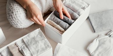 A girl sitting on the floor folding clothes into boxes