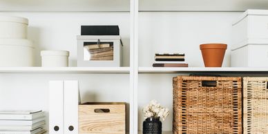 White shelves with neatly organised items on display including baskets files and plants