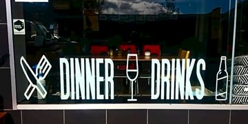 Dinner Drinks written poster on the glass of a store