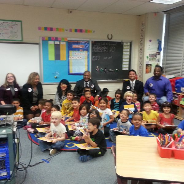 Group of young students and adults posing happily in a classroom.