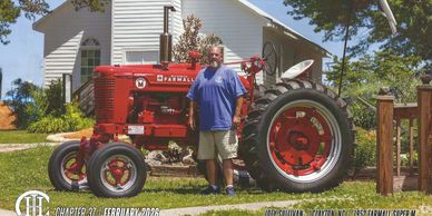 Man standing next to a red Farmall tractor.