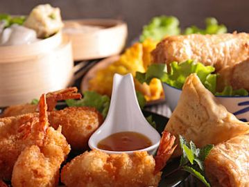 Assorted crispy fried appetizers with dipping sauce on a plate.