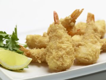 Crispy fried shrimp with a lemon wedge and parsley garnish on a white plate.
