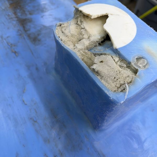 Close-up of a damaged blue plastic object with white brittle material inside.