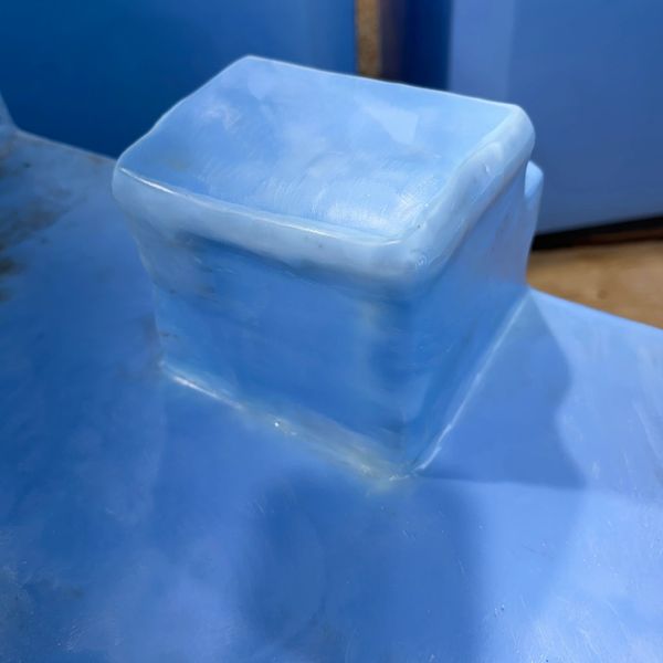 Close-up of a translucent blue ice cube on a smooth surface.