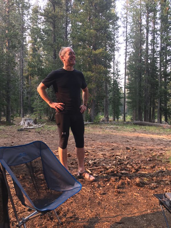 Man in athletic wear standing in a forest clearing.