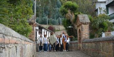 Group of women walking on a cobblestone path in a scenic, green area.