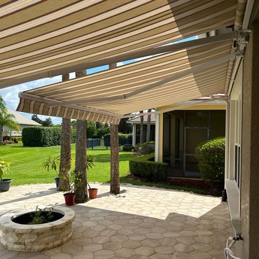 Striped awnings providing shade on a patio with greenery.