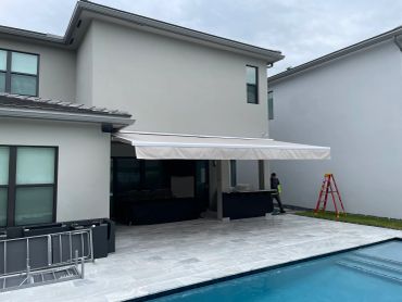 Modern two-story house with pool and awning.