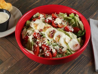 A fresh chopped wedge salad featuring crisp iceberg lettuce, smoky bacon, ripe tomatoes, blue cheese