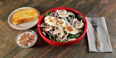 Fresh spinach salad with mushrooms, red onion, hard-boiled egg, and warm bacon poppy seed dressing a