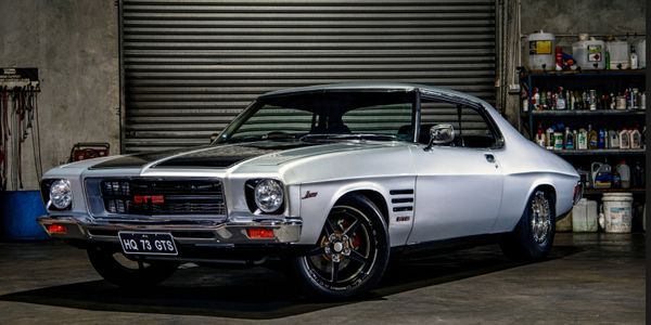 Classic silver Holden HQ GTS muscle car in a garage.