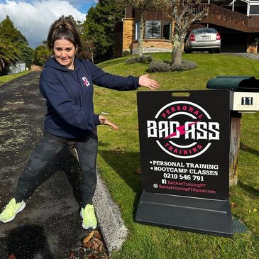 Woman pointing at a Personal Training sign outdoors on a sunny day.