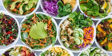 Colorful fresh salads with vegetables and avocado in bowls.