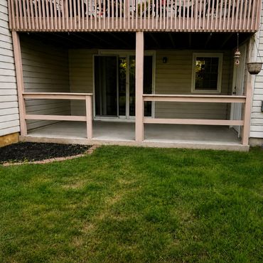 Small patio under balcony with green grass lawn.